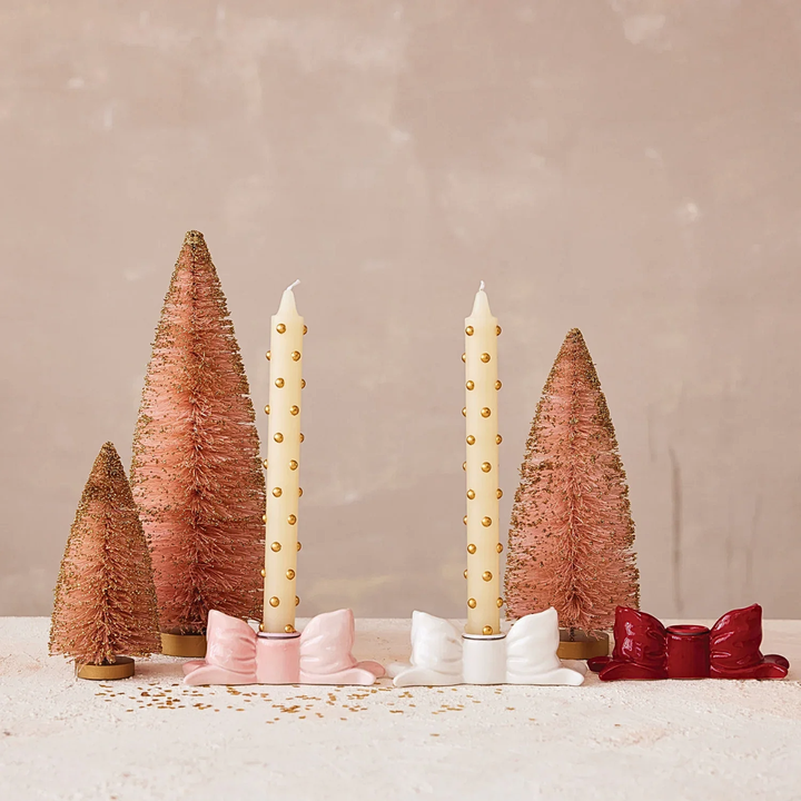 Decorative setup with candles and bottle brush trees on a neutral background