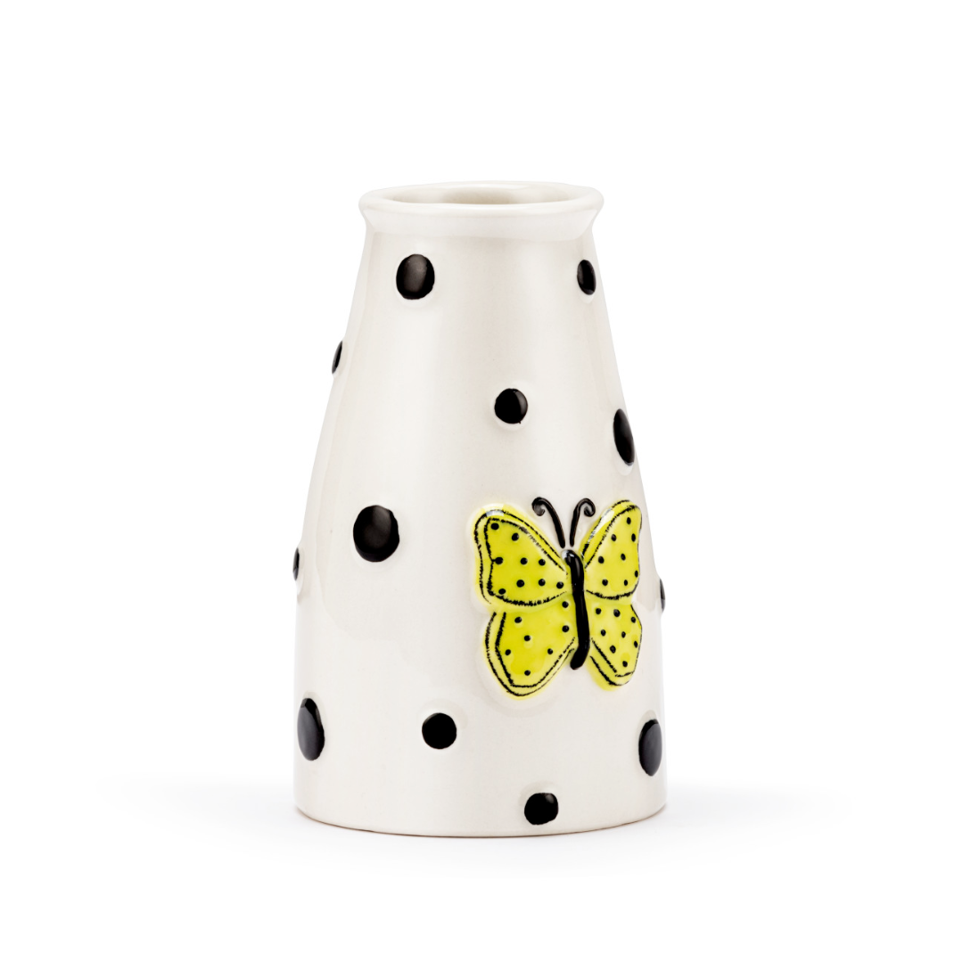 White vase with black polka dots and a yellow butterfly design on a white background