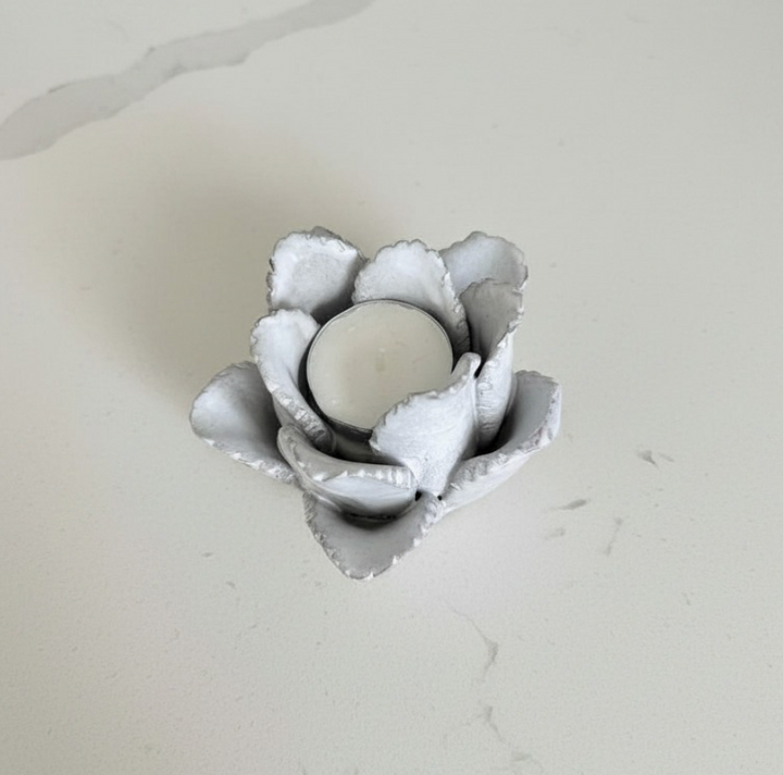 Floral-shaped candle holder with a candle on a light gray background