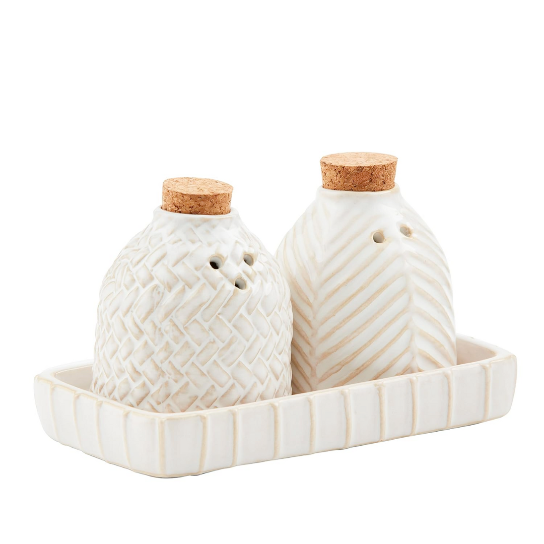 Two ceramic salt and pepper shakers with cork lids on a matching tray.