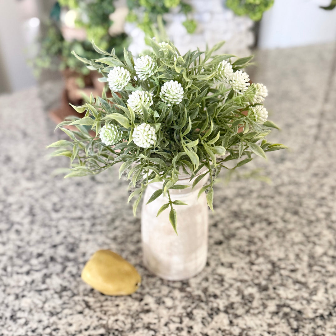 Artificial green plant in a clear vase on a granite countertop