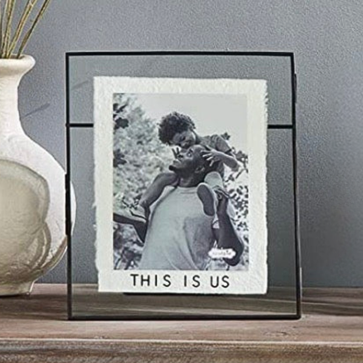 Framed photo of a couple with 'THIS IS US' text on a gray wall background