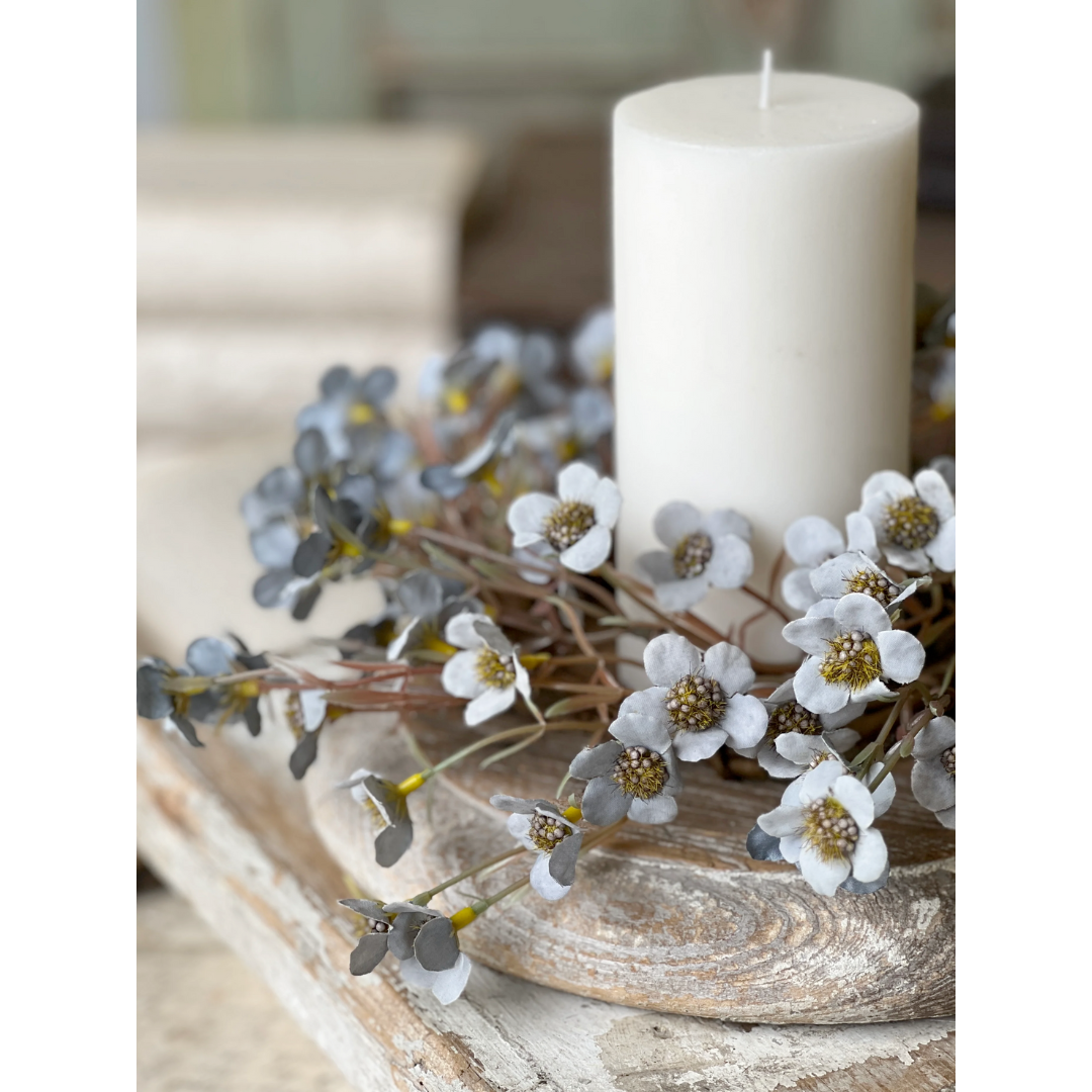 Blue floral candle ring on a wooden surface with decorative flowers