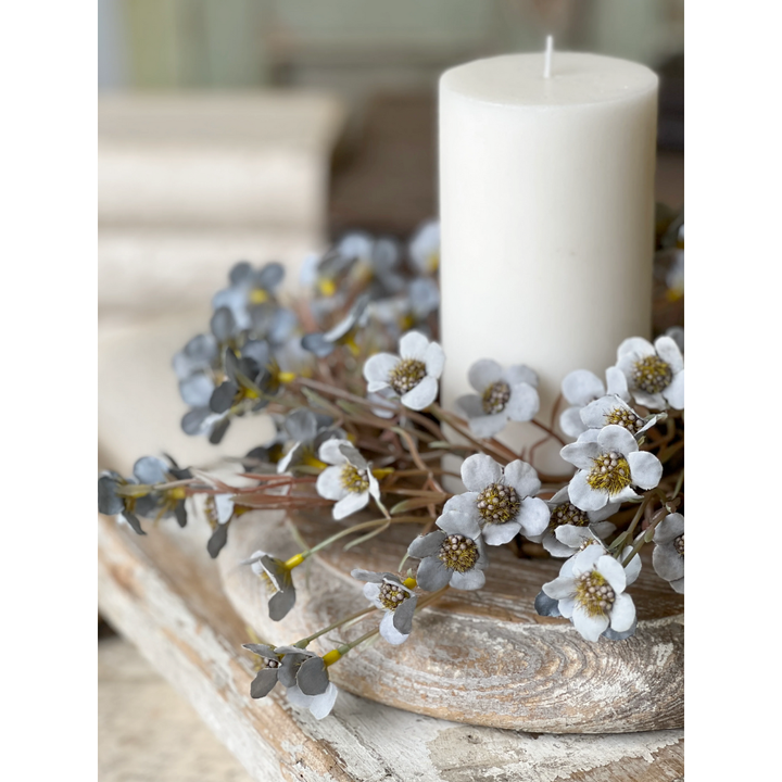 Blue floral candle ring on a wooden surface with decorative flowers