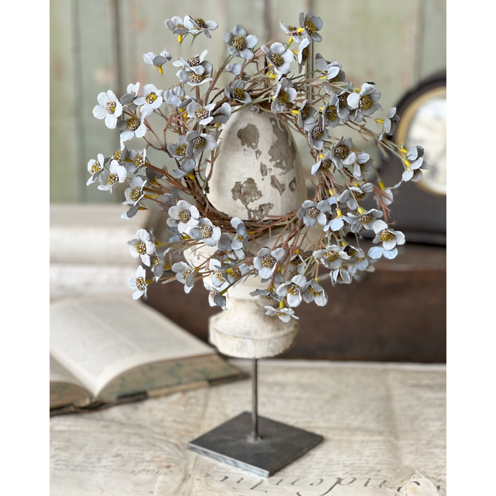 Decorative arrangement with blue floral candle ring and on a stand in a home setting