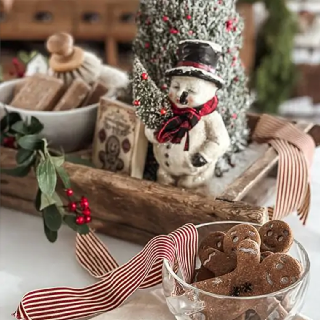 Christmas-themed table setting with gingerbread cookies, a snowman figurine, and decorative elements.