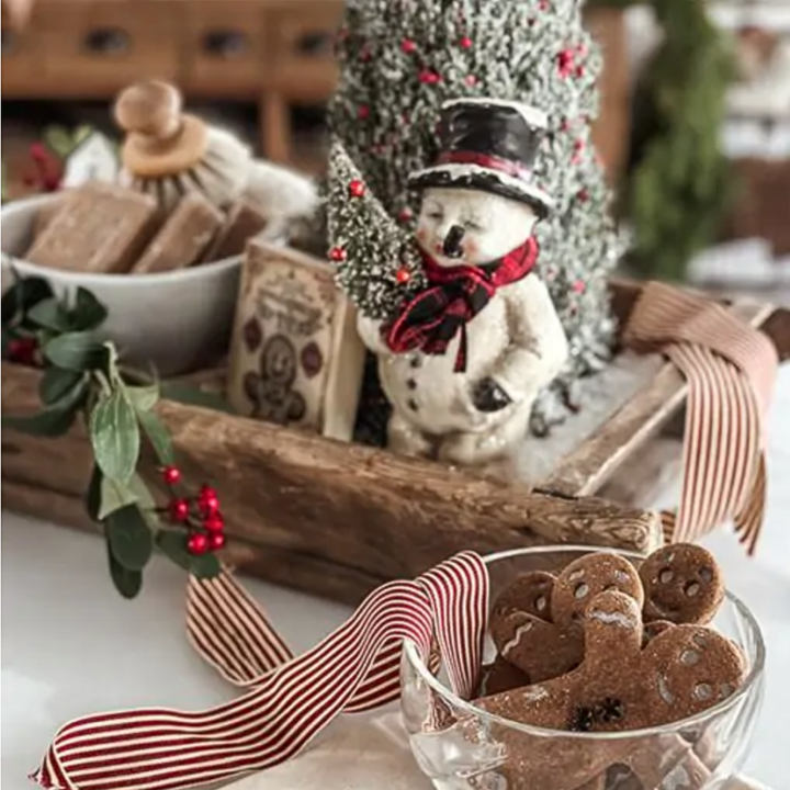 Christmas-themed table setting with gingerbread cookies, a snowman figurine, and decorative elements.