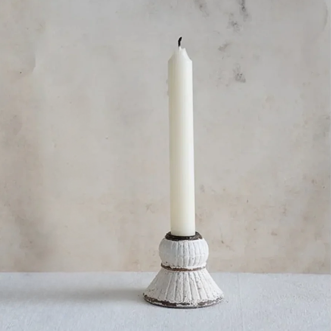 White candle in a textured candle holder on a marble surface