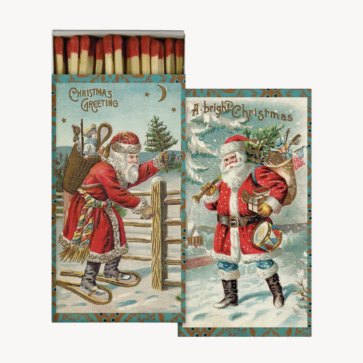 A set of vintage Christmas-themed matchboxes with images of Santa Claus and holiday greetings. The matchboxes have a festive design, primarily in red and green colors, with text and graphics related to the holiday season.