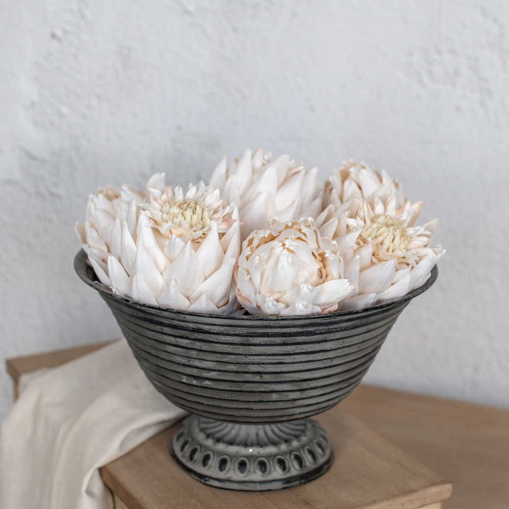 Decorative bowl with Cream Artichoke Heads on a wooden surface against a light background