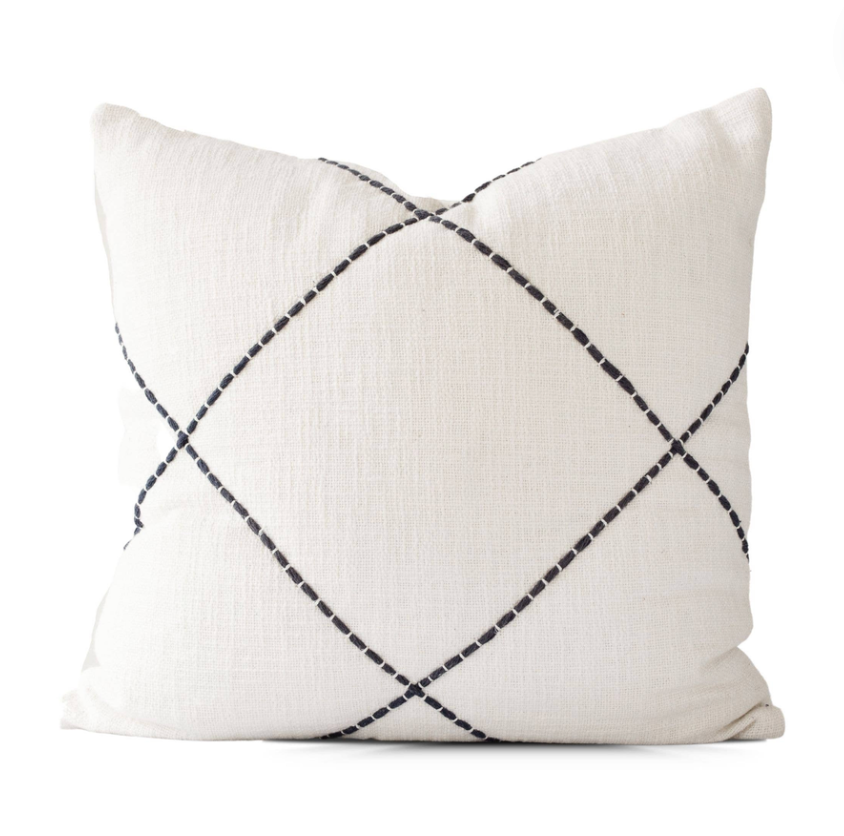 White embroidered pillow cover with a crisscross pattern, on a white background