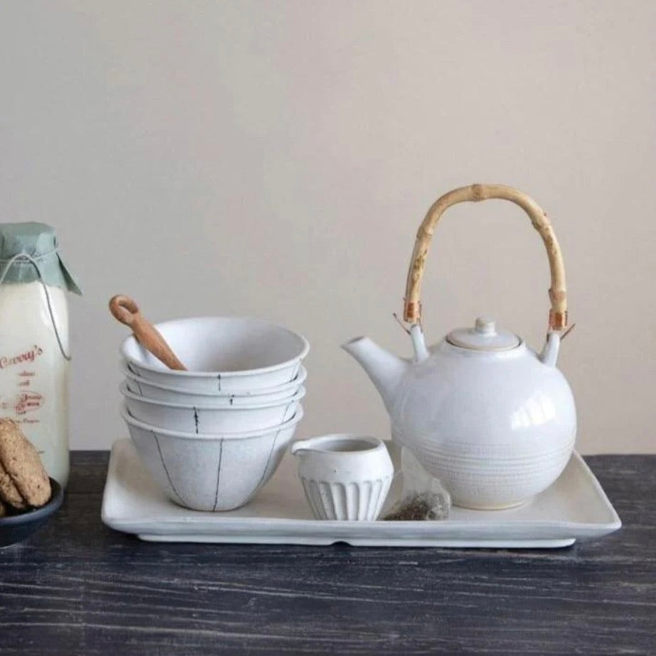A white handcrafted stoneware tray with a speckled creamy-white matte finish, displayed alongside a teapot and bowls set.