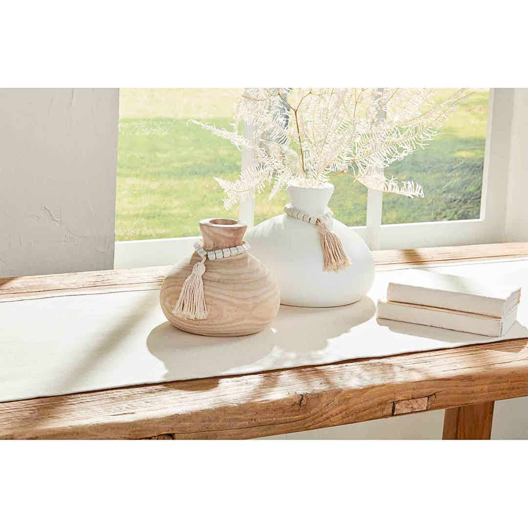 Two decorative vases on a wooden table with a scenic view outside.