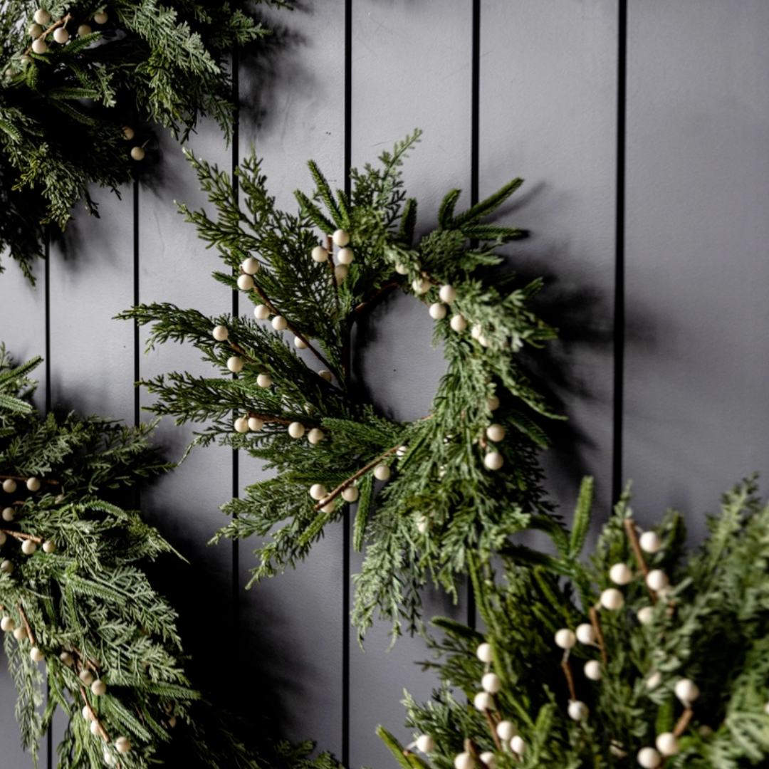 Green wreaths with white berries on a dark wooden background