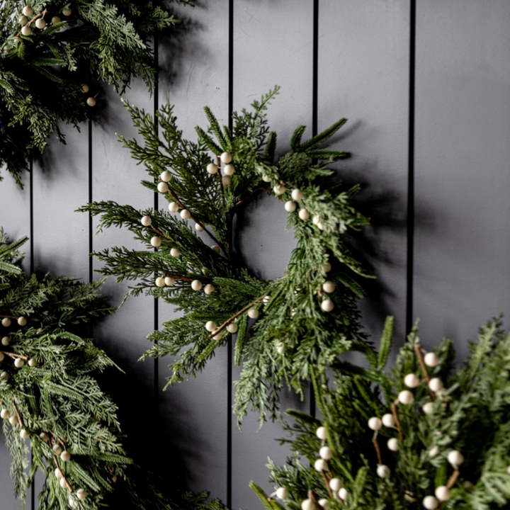 Green wreaths with white berries on a dark wooden background