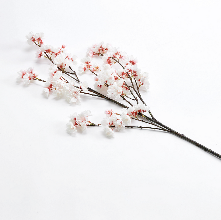 White and pink artificial cherry blossom flower branch on a white background