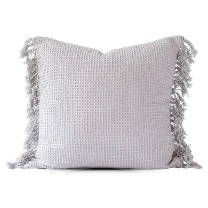 Gray textured pillow with tassels on a white background