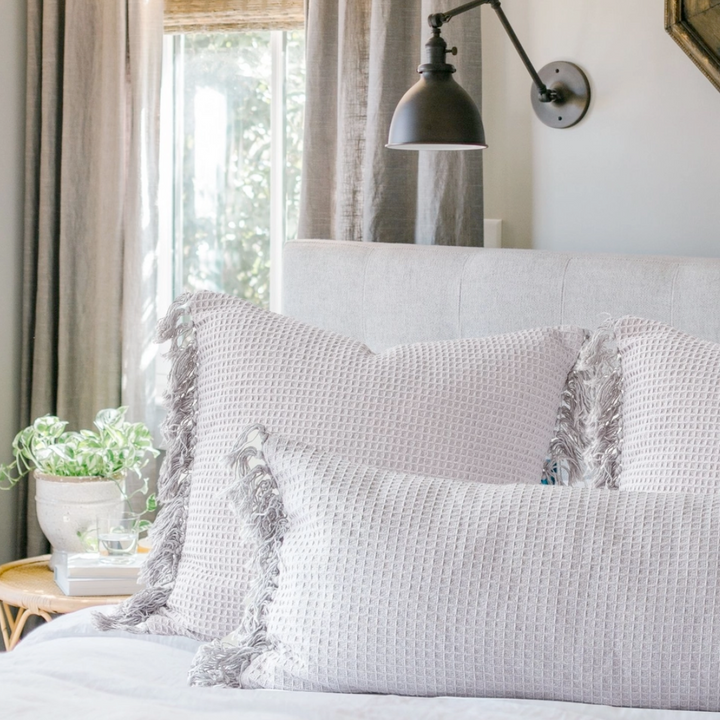 Neatly made bed with decorative pillows in a bedroom setting.