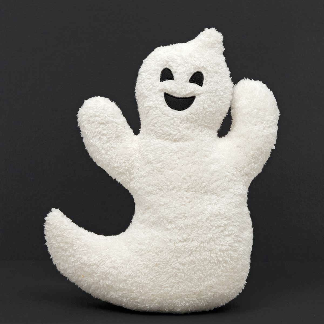A white, ghost-shaped sherpa pillow with a happy facial expression designed for Halloween decoration.