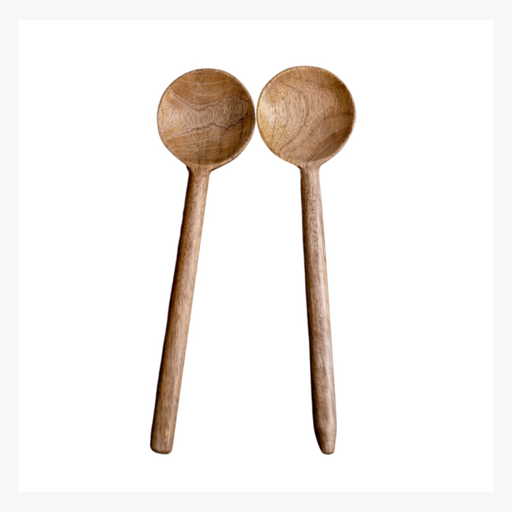 A pair of hand carved mango wood serving spoons with a smooth matte finish.