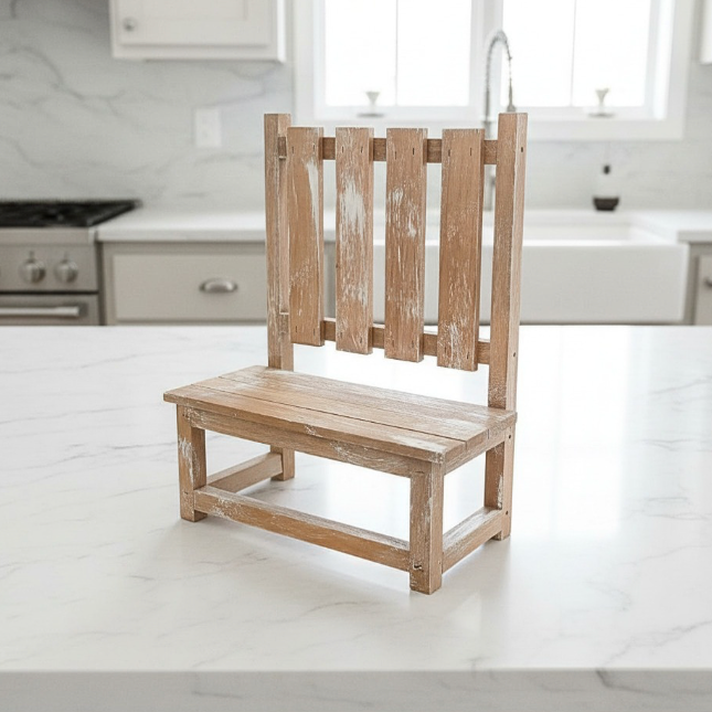 A wooden plant stand bench with a distressed, whitewashed finish, set on a white marble kitchen island.