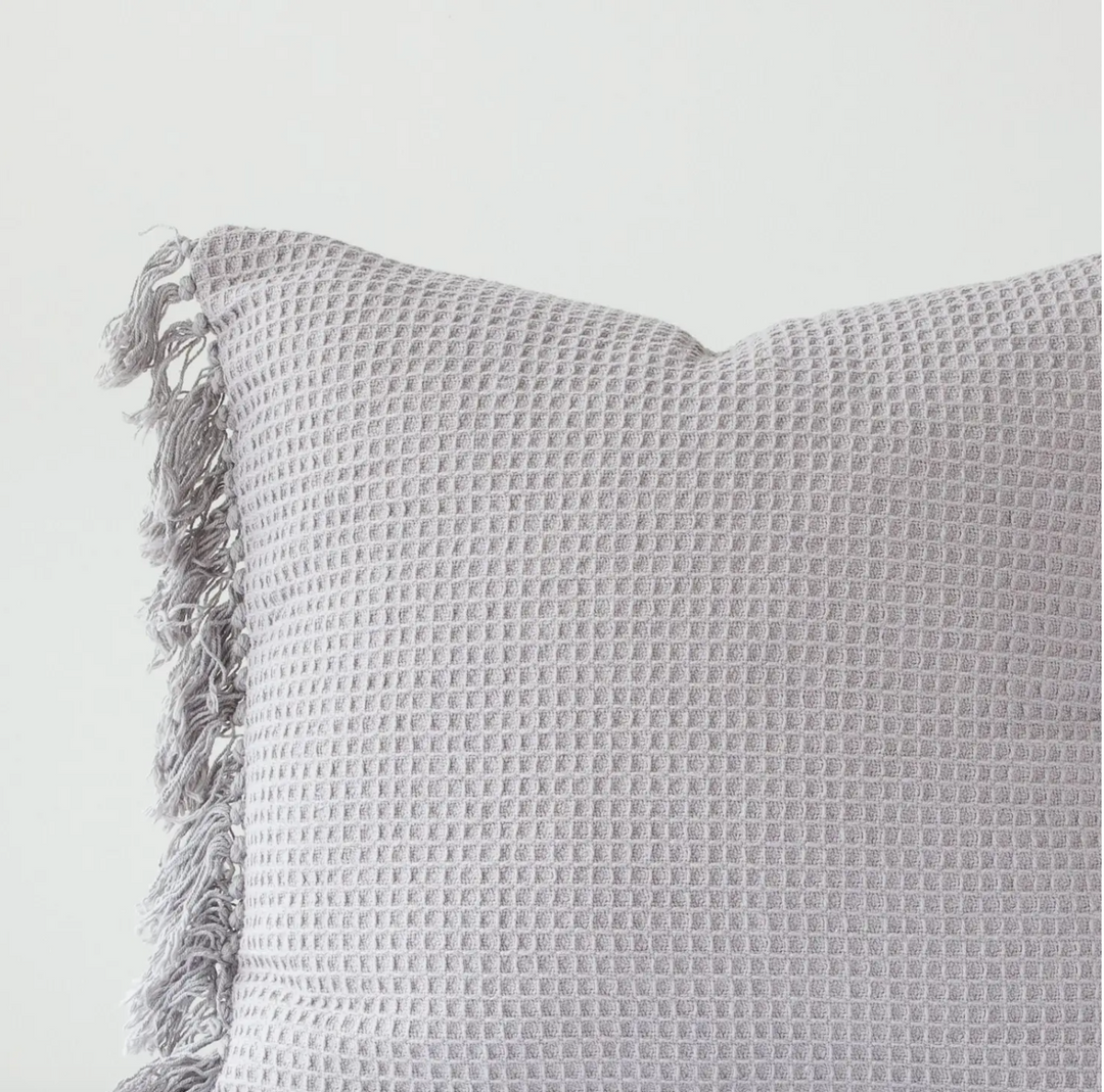 A gray waffle weave euro pillow cover with fringe edges on a white background.