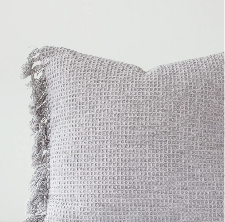A gray waffle weave euro pillow cover with fringe edges on a white background.
